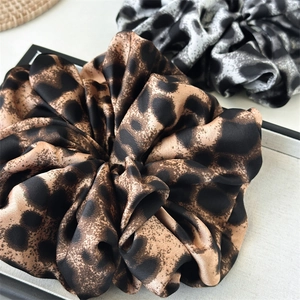 Close-up of oversized leopard print and ink-patterned satin scrunchies with silky texture