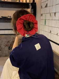Detail of red fabric scrunchie with heart label on a bun hairstyle with blue shirt