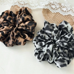 Detailed macro of leopard print satin scrunchies in brown and grey fabric patterns