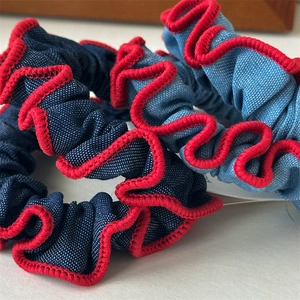 Detail von Denim Haargummis in Blautönen mit roten Nähten und Wellenstruktur