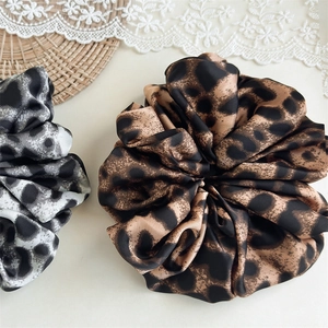 Close-up of brown and grey leopard print satin scrunchies with silky texture