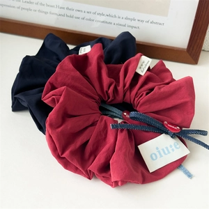 Detail of navy and dark red scrunchies with fabric labels and denim bow accents