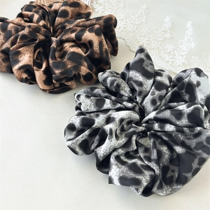 Detailed view of large leopard print scrunchies in brown and grey satin fabric