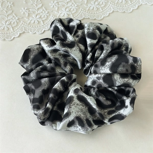 Macro shot of silk satin leopard print hair scrunchie with smooth fabric texture