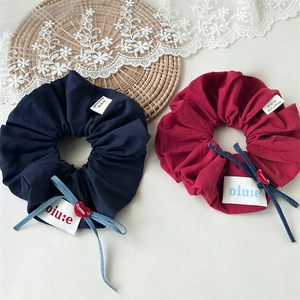 Detailed shot of scrunchies with denim bows and red heart charms on a lace mat
