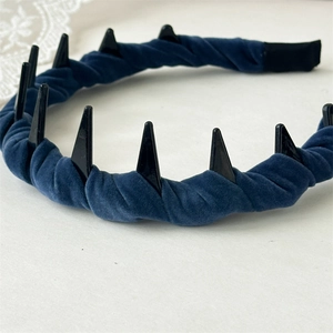Detail of dark blue velvet twisted headband featuring black spike studs and wavy design