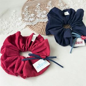 Detail of burgundy and navy scrunchies with denim bows and heart charms on lace