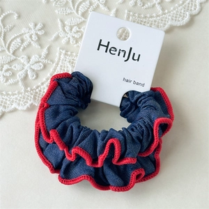 Detail von blauen Denim-Haargummis mit roten Wellenkanten auf weißem Spitzenstoff