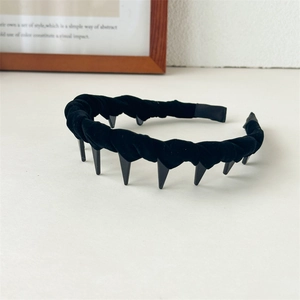 Detailed close-up of retro black velvet headband with sharp zigzag comb teeth texture
