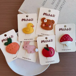 Detail view of handmade cartoon leather hair clips with cute animal and fruit embroidery