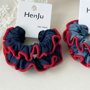 Detail von blauen Denim-Haargummis mit roten Wellenkanten auf weißer Displaykarte