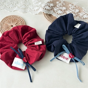Detail of oversized fabric scrunchies with denim bows and heart charms in red and navy