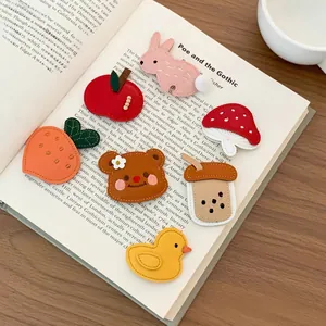 Detailed close-up of cute embroidered animal hair clips on an open vintage book page