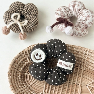 Dreiteiliges Blumen-Haargummi-Set mit Schleifen und Pompons auf einem Tablett