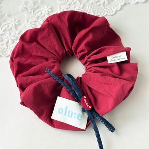 Detailed macro view of burgundy fabric scrunchie with blue bow and heart pendant