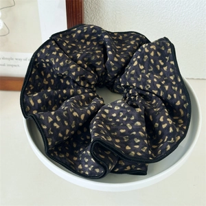 Detail of leopard print scrunchie in a white ceramic bowl with nordic home decor background