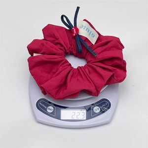 Detail of red fabric scrunchie with blue denim bow and heart charm on a scale