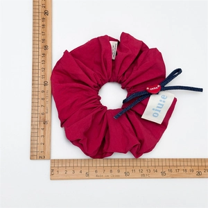 Magenta oversized scrunchie with blue denim cord, heart charm, and white brand tag