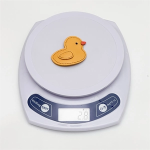 Detail showing a 2.8g lightweight orange leather duck hair clip on a digital scale