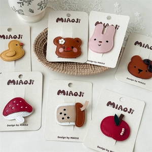 Detailed close-up of cute leather cartoon hair clips with animal and fruit motifs