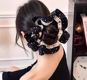 Detailed view of large black polka dot scrunchie with lace trim on a bun hairstyle
