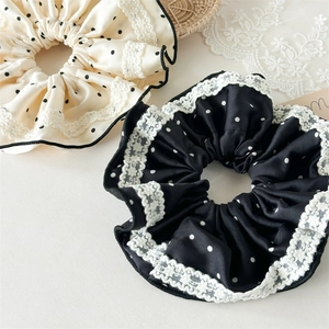 Close-up of elegant satin polka dot scrunchie with delicate lace trim edges