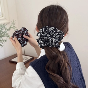 Détail de chouchous en mousseline fleurie en noir et marron portés dans les cheveux