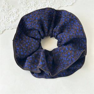 Detail of floral print scrunchie with blue animal spots and delicate overlock edge