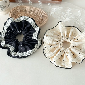 Close-up of oversized lace polka dot satin scrunchies in black and beige colors