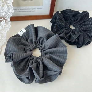 Striped fabric scrunchies in black and dark grey colors with minimalist bow logo labels