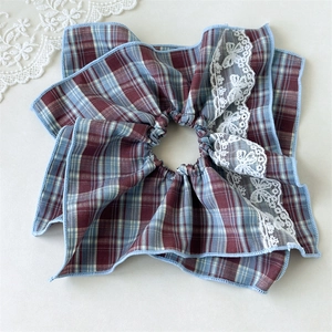 Detailed close-up of retro plaid hair scrunchie with lace bow embroidery and ruffled edge