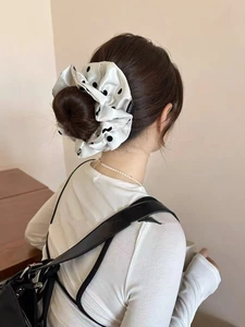 Detail of white satin scrunchie with black polka dots on a woman's bun hairstyle