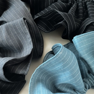 Close-up of striped fabric scrunchies in black, gray, and blue with twill texture