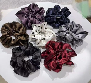 Detail of satin scrunchies set in seven colors with fashion woven labels on white tray