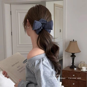 Detailed view of navy plaid bow scrunchie on a low ponytail for vintage preppy look