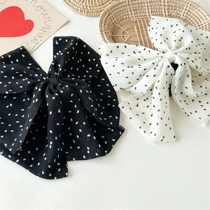 Détail de grandes barrettes à nœuds à pois en mousseline chic noir et blanc pour femmes
