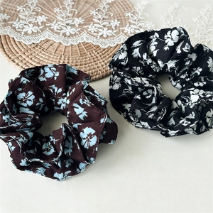 Détails de chouchous à fleurs café et noirs avec une élégante texture de tissu plissé
