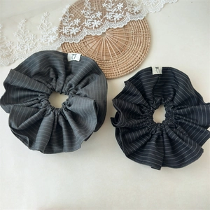 Close-up of striped fabric scrunchies with white woven labels on a bamboo tray
