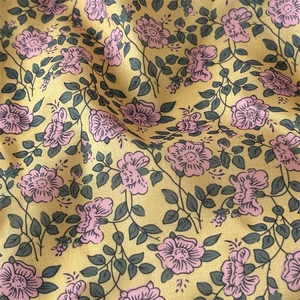 Macro detail of high-quality floral fabric with pink roses on yellow background
