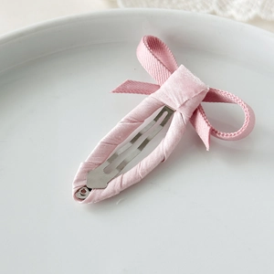 Dettaglio macro di un fermaglio per capelli a fiocco rosa su un piatto di ceramica bianca
