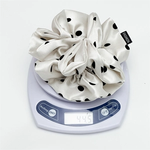 Detailed view of beige polka dot satin scrunchie weighing 44.5 grams on a digital scale