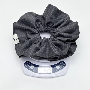 Grey striped scrunchie with woven bow label weighing 42.5g on a digital scale