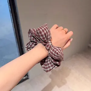 Detailed view of red and white plaid bow hair scrunchie made of cotton fabric texture