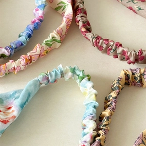 Close-up of colorful floral print scrunchies with elastic pleats and soft texture