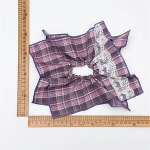 Detail showing the purple plaid fabric and white floral lace trim of the hair scrunchie