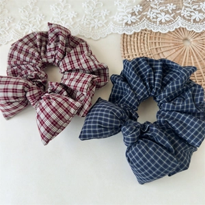 Detail of vintage red and blue plaid bow scrunchies on a decorative lace background