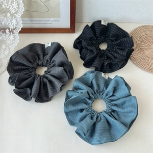 Detailed view of striped fabric scrunchies in charcoal, black, and mist blue colors