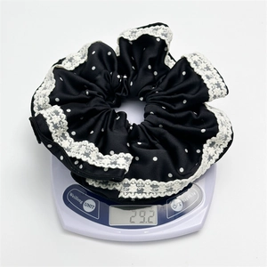 Close-up of black satin polka dot scrunchie with lace trim on a scale weighing 29.2g