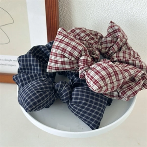 Retro plaid bow scrunchie set in navy and red fabric on a white ceramic plate