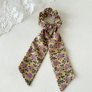 Close-up of floral print scrunchie with long ribbons on soft white lace background
